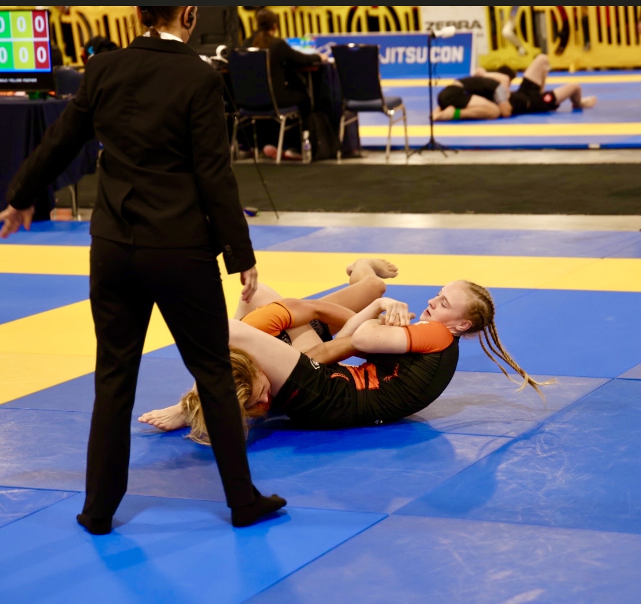 Wettkampfbild aus dem Turnierbaum der IBJJF Pan Kids No-Gi Championship 2024. Die abgebildete Person befindet sich in einer oberen Kontrollposition. IBJJF-sanktioniertes Wettkampfumfeld mit Wertungstisch und angrenzenden Matten im Hintergrund.